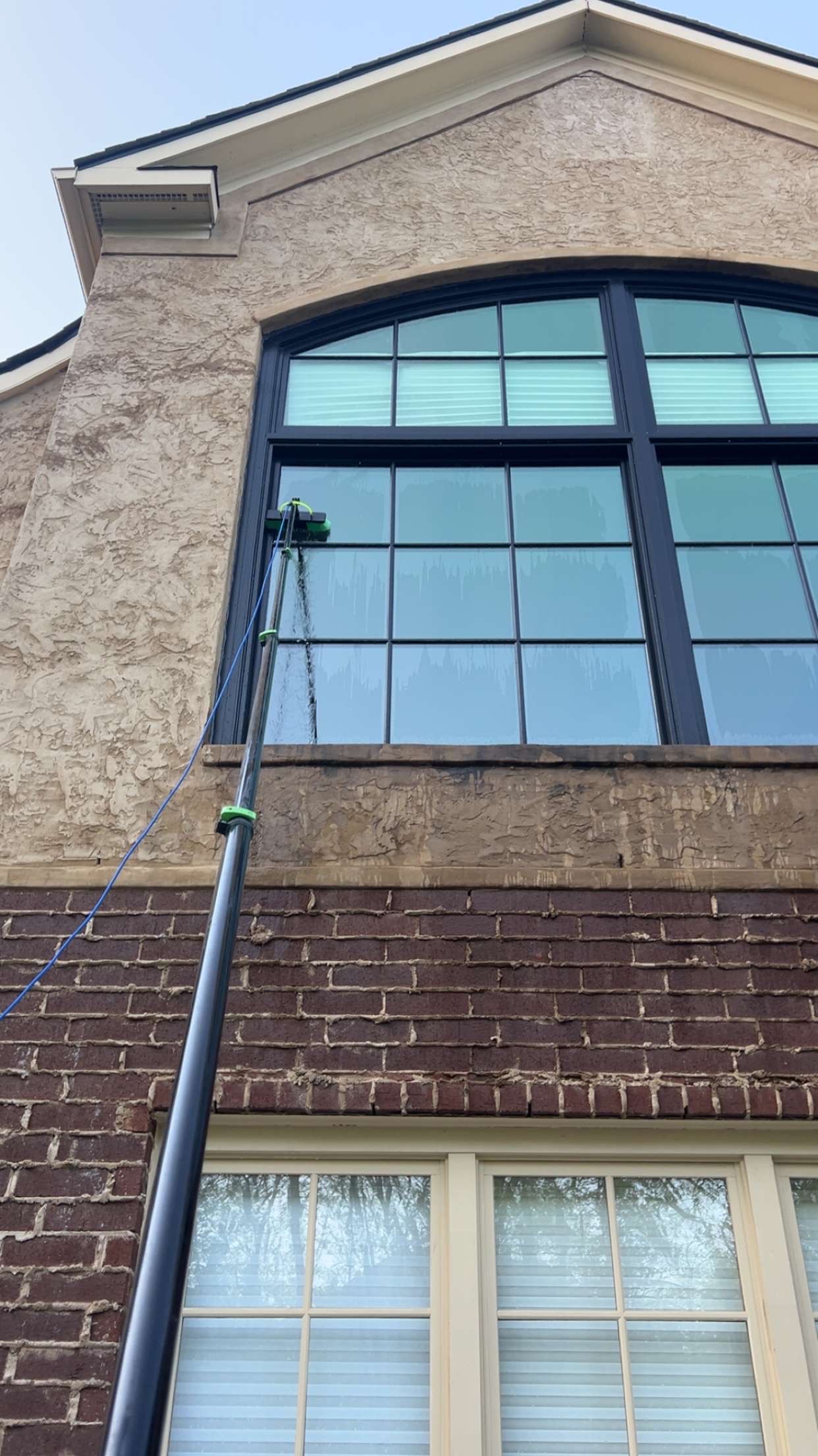 Professional window cleaner using a water-fed pole system to clean high windows